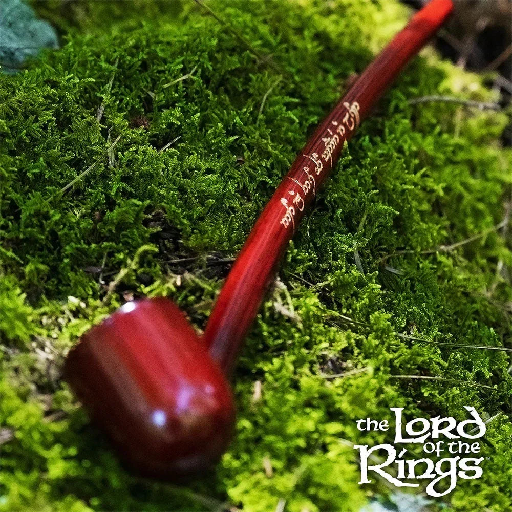 Red wooden smoking pipe with Elvish script lying on green moss, Lord of the Rings themed.