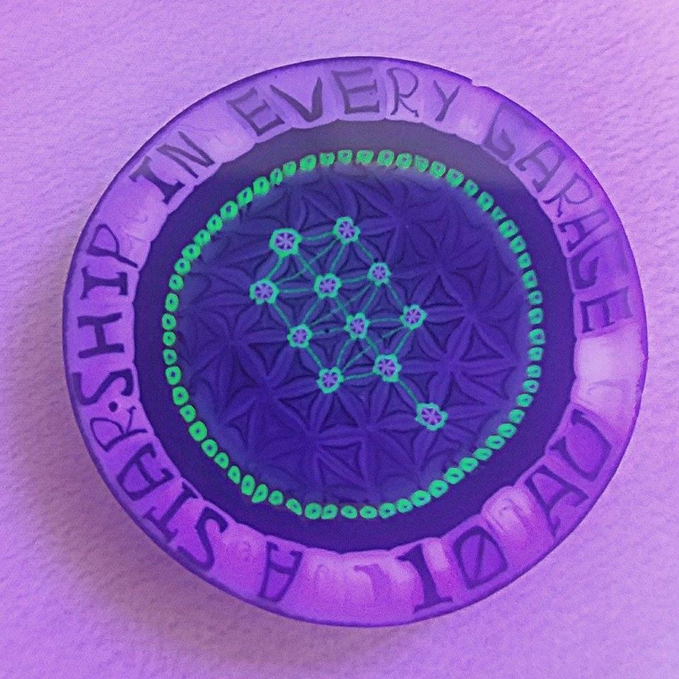 Purple glass tray with geometric pattern and glowing green accents, phrase around edge.