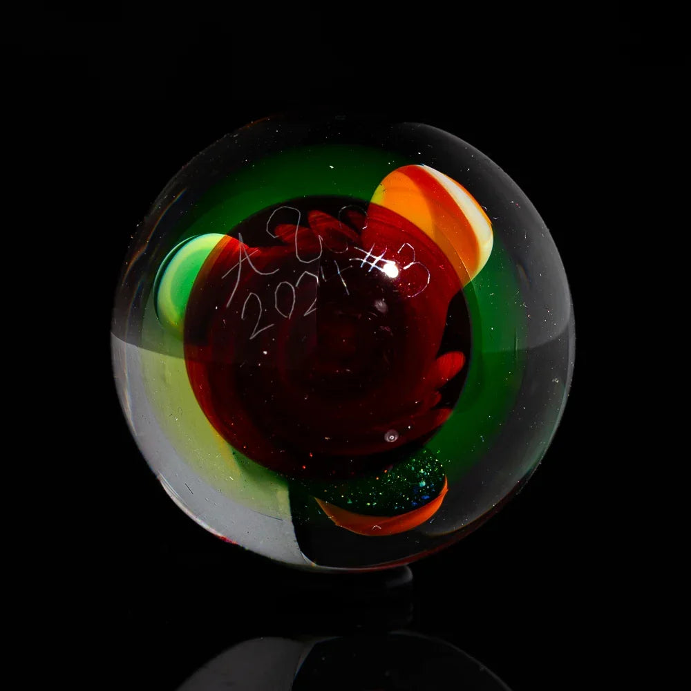 Colorful art glass marble with red, green, and yellow swirls on black background