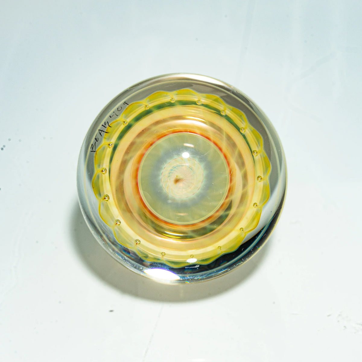 Heady glass marble with intricate yellow and orange spiral design on white background