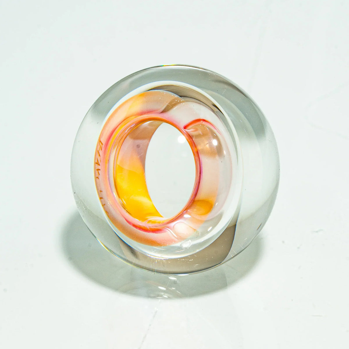 Hand-blown glass carb cap with clear and orange-yellow swirl design on white background