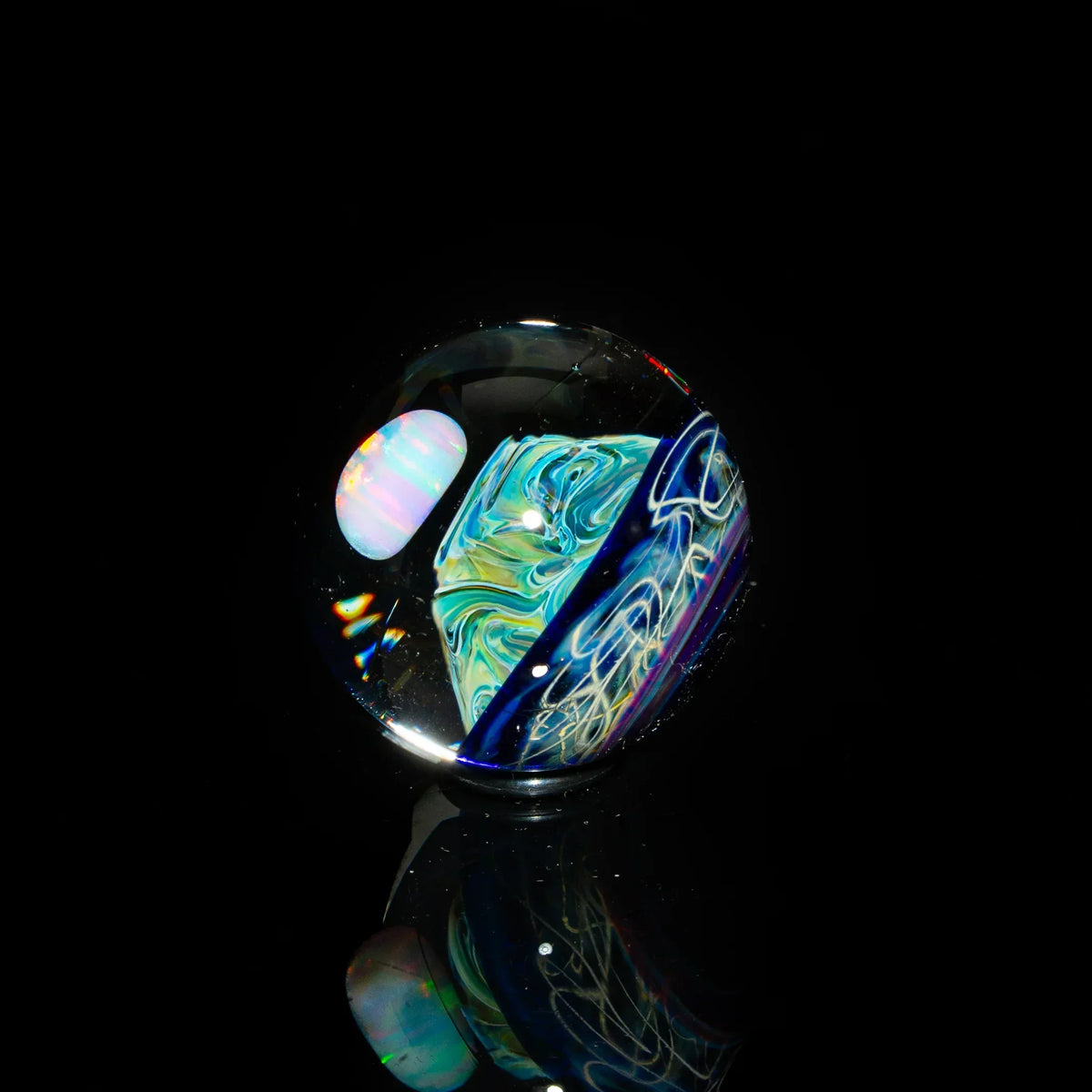 Handcrafted glass marble with swirling blue, yellow, and opal-like patterns on black background