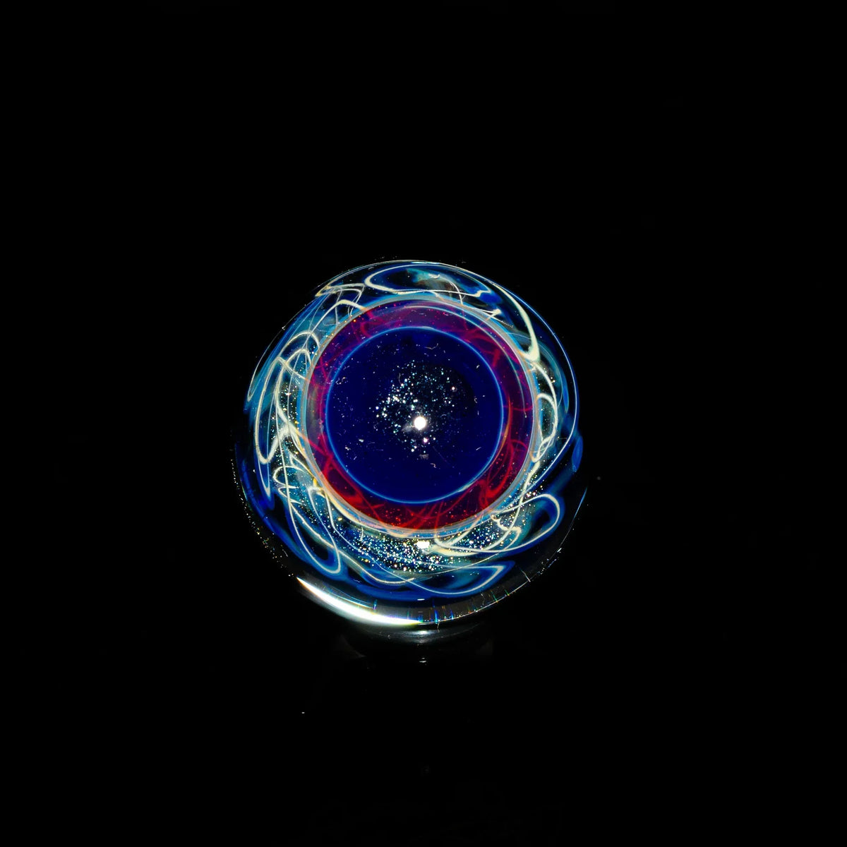 Colorful heady glass marble with swirling blue, red, and white patterns on black background