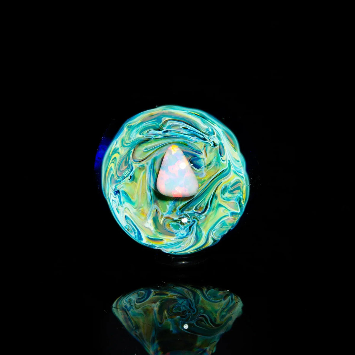 Colorful heady glass marble with opal inlay on reflective black background