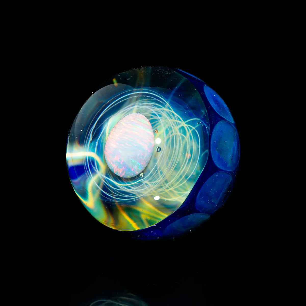 Heady glass marble with blue galaxy pattern and opal centerpiece on black background