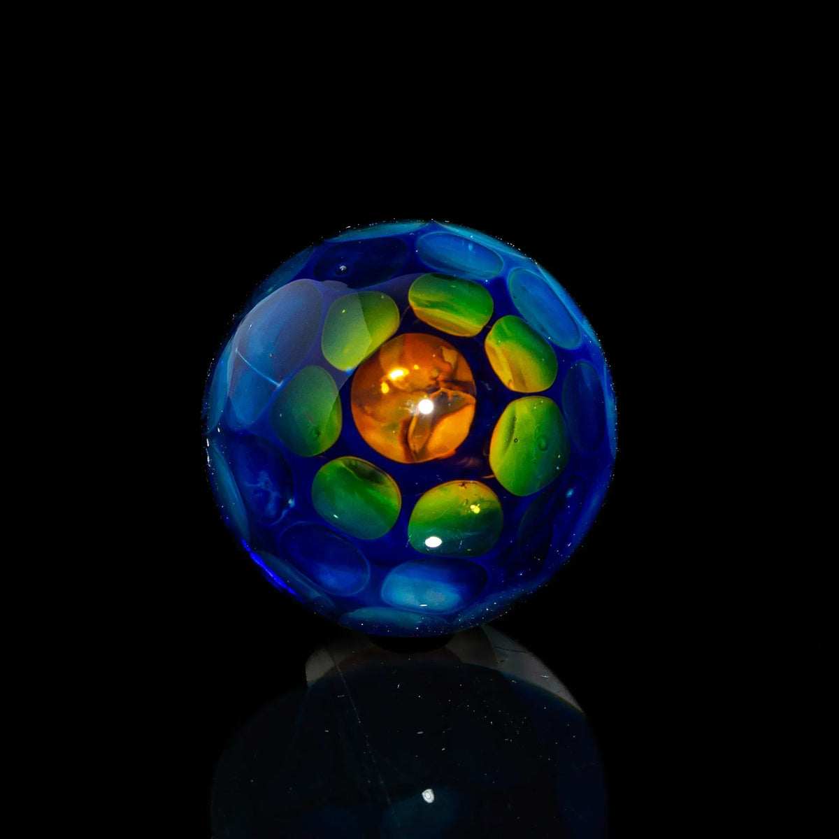 Colorful glass marble with blue, green, and orange details on a black background
