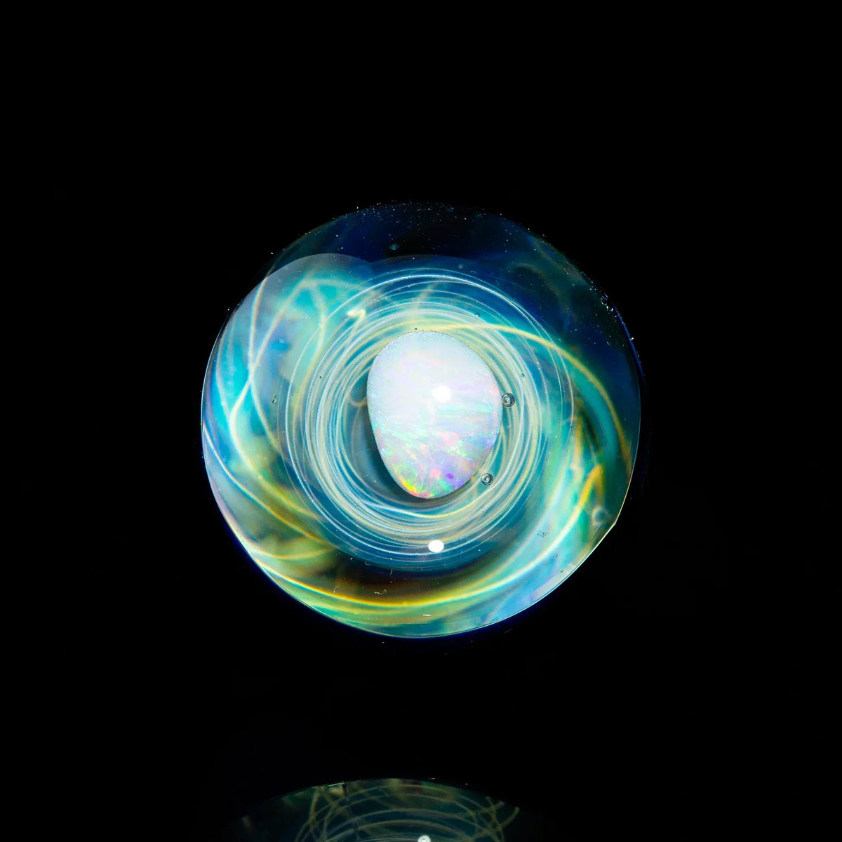 Heady glass marble with opal core and swirling blue and gold accents on a black background