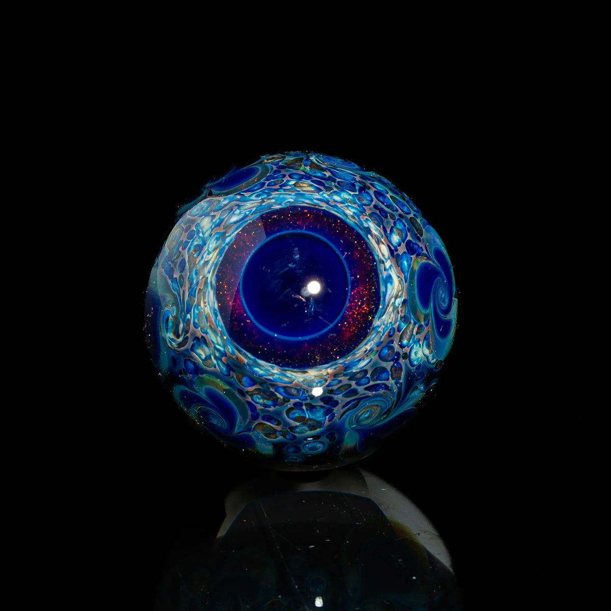 Handcrafted blue glass marble with intricate swirling patterns on black background