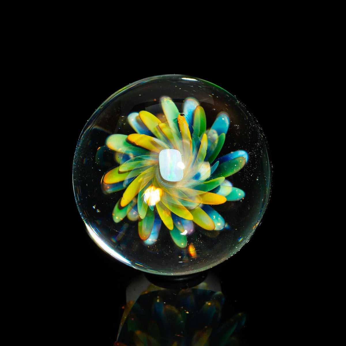 Handcrafted glass marble with vibrant flower design and opal centerpiece on black background