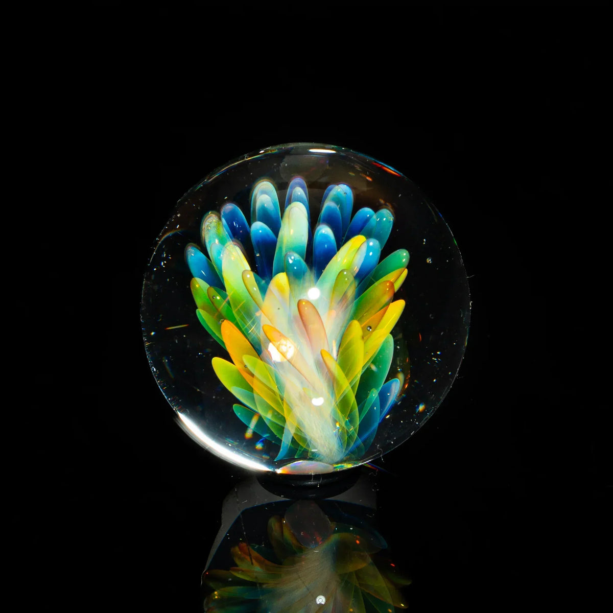 Colorful glass art marble with vibrant feather-like patterns on black background