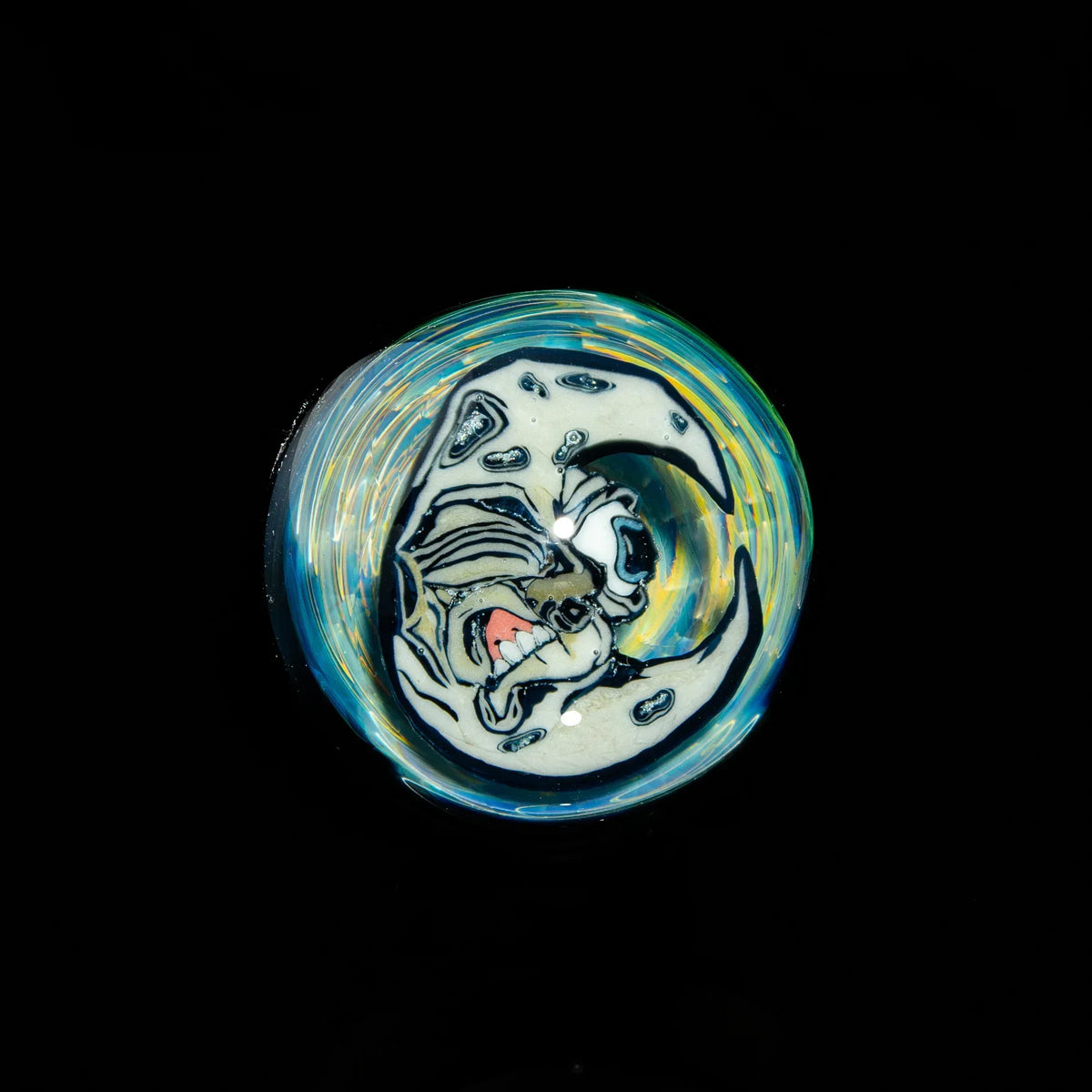 Heady glass marble with swirling colors and detailed moon face design on black background