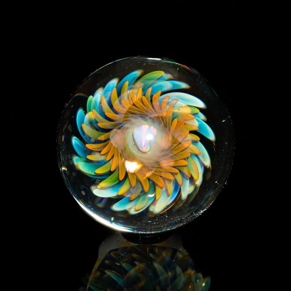 Handcrafted glass marble with colorful swirling flower design on black background