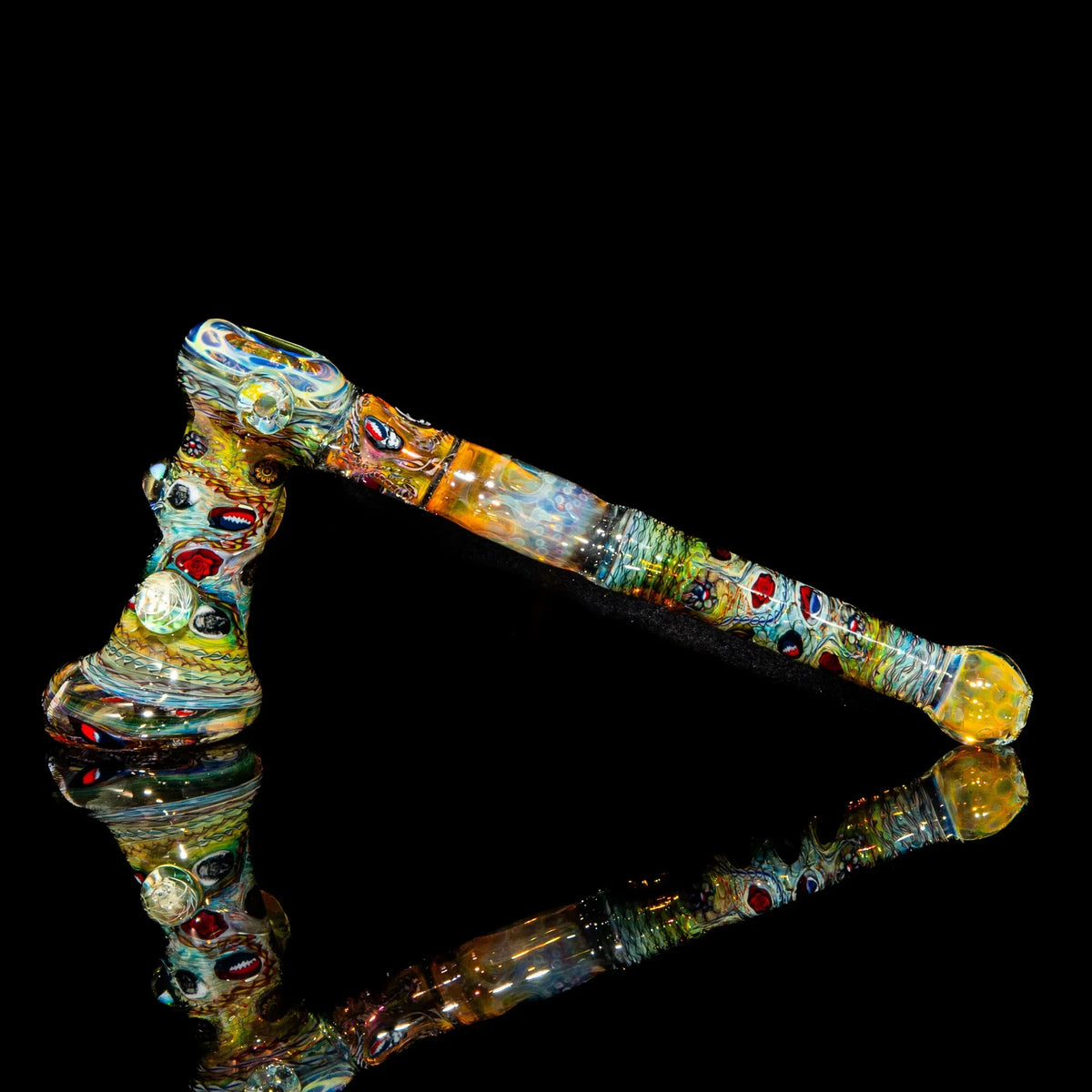 Colorful heady glass hammer pipe with intricate designs on a black reflective background