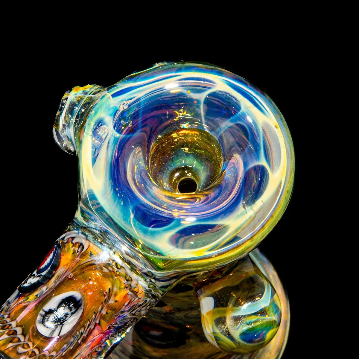 Close-up of a colorful hand-blown glass pipe with intricate swirling patterns on black background.