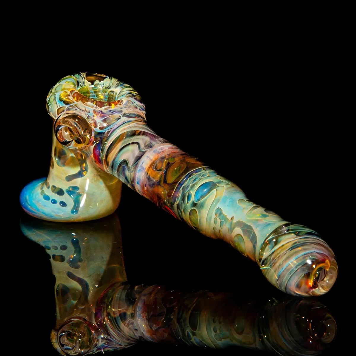 Handcrafted multicolor glass pipe with unique patterns on a black reflective surface