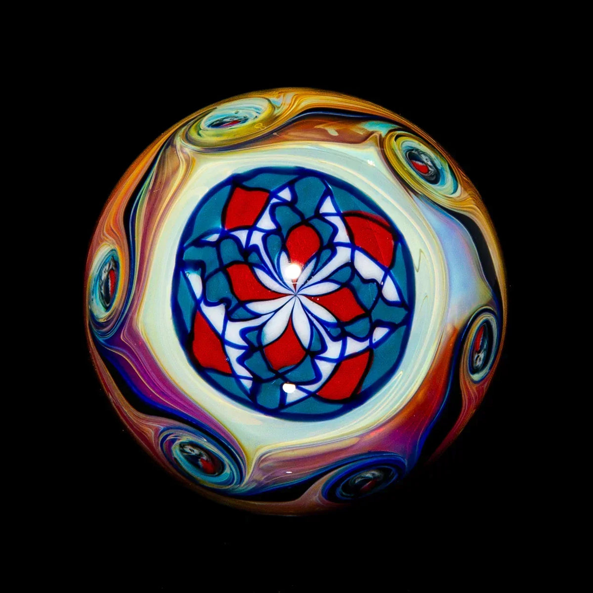 Hand-blown glass marble with intricate red, blue, and white mandala design on black background