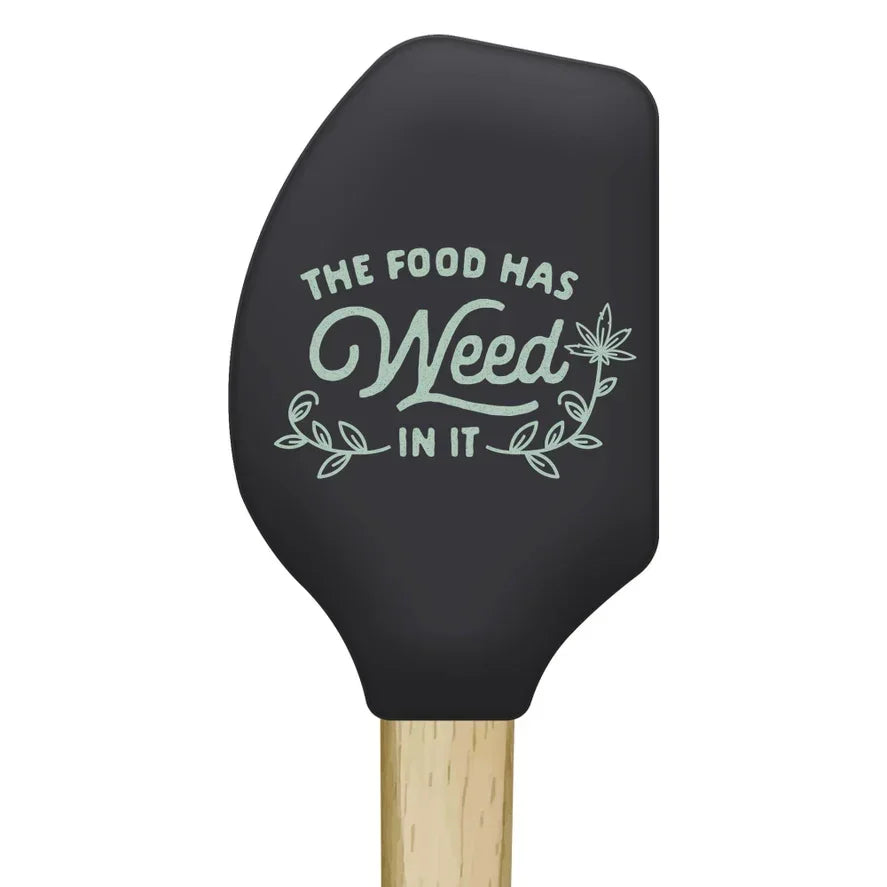 Black silicone spatula with 'The food has weed in it' text and leaf graphic, wood handle