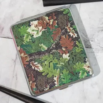 Rectangular metal case with forest camo leaf design on marble surface