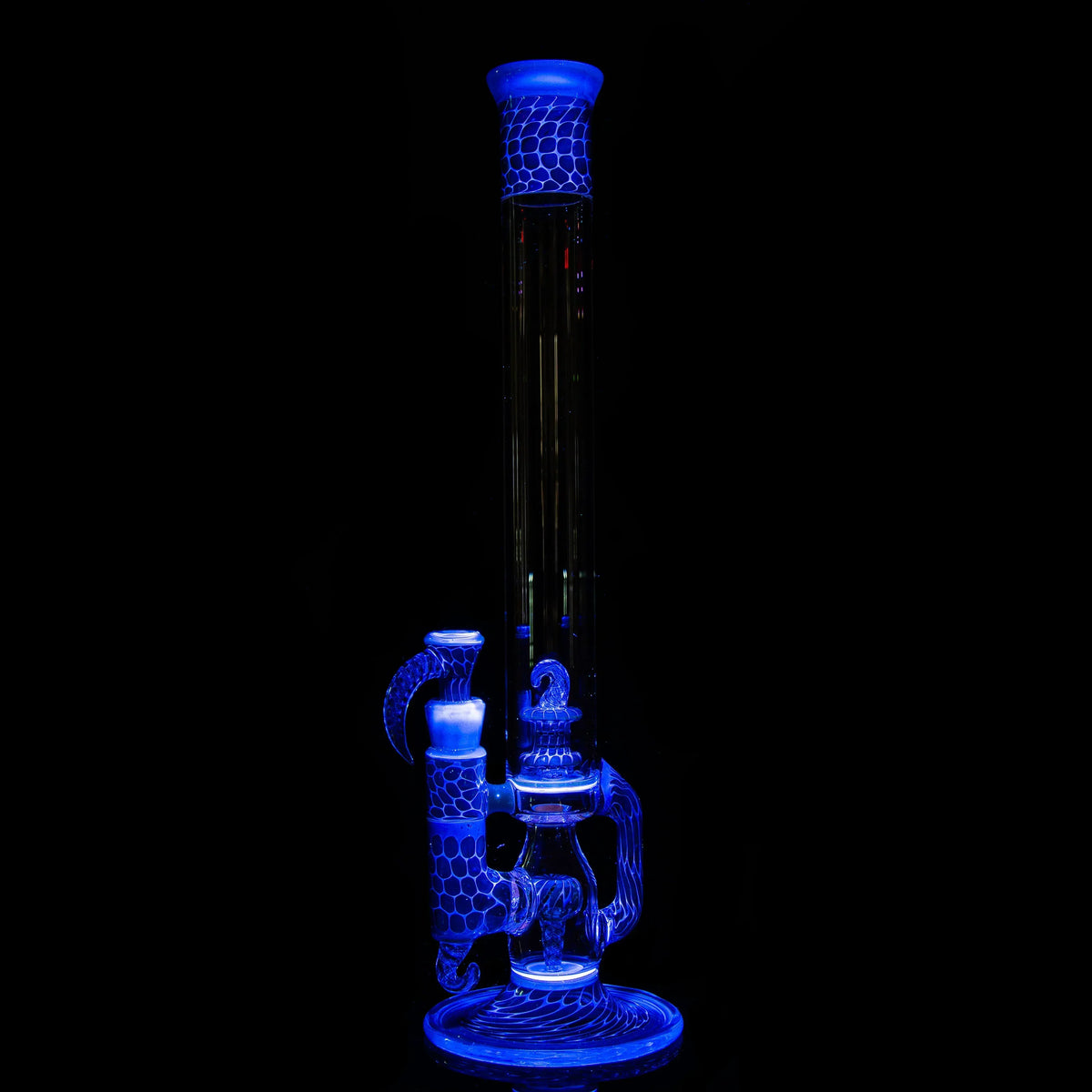 UV-reactive glass bong with intricate honeycomb design glowing blue in dark setting