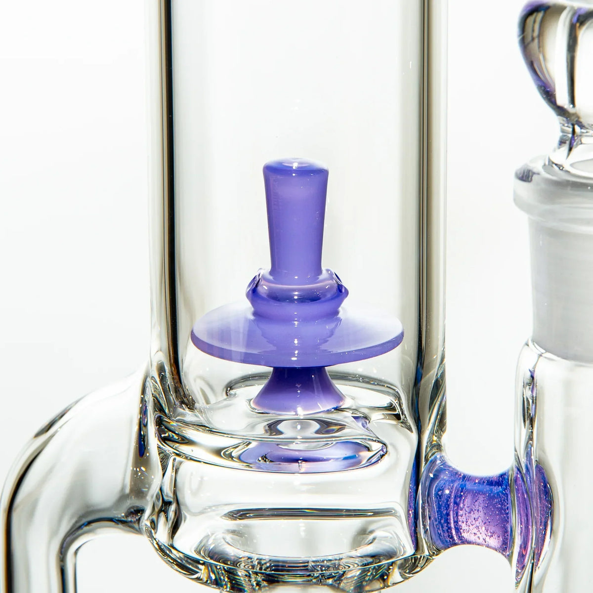 Close-up of clear glass water pipe with purple glass percolator detail