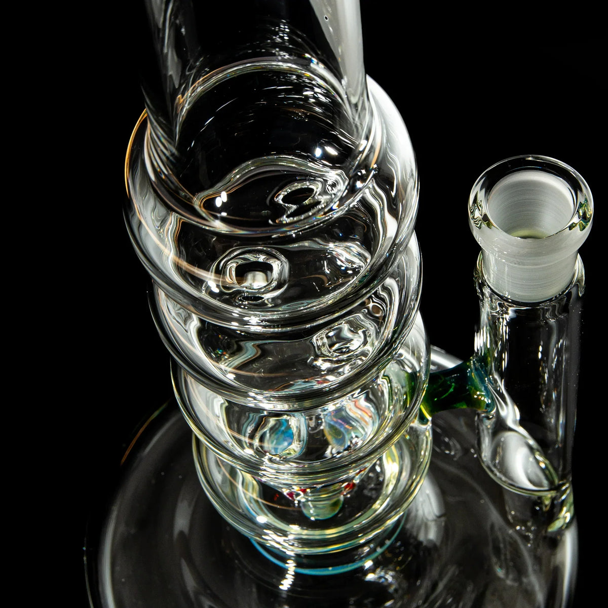 Close-up of a clear glass water pipe with spiral design on a black background