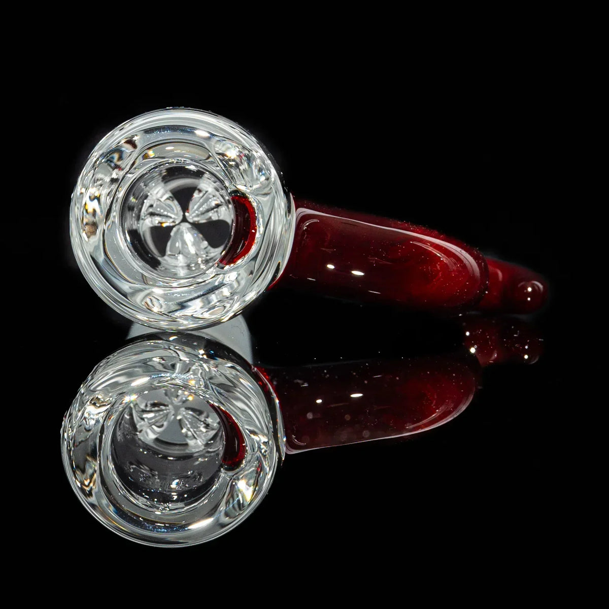 Hand-blown glass pipe with clear bowl and deep red stem on black background
