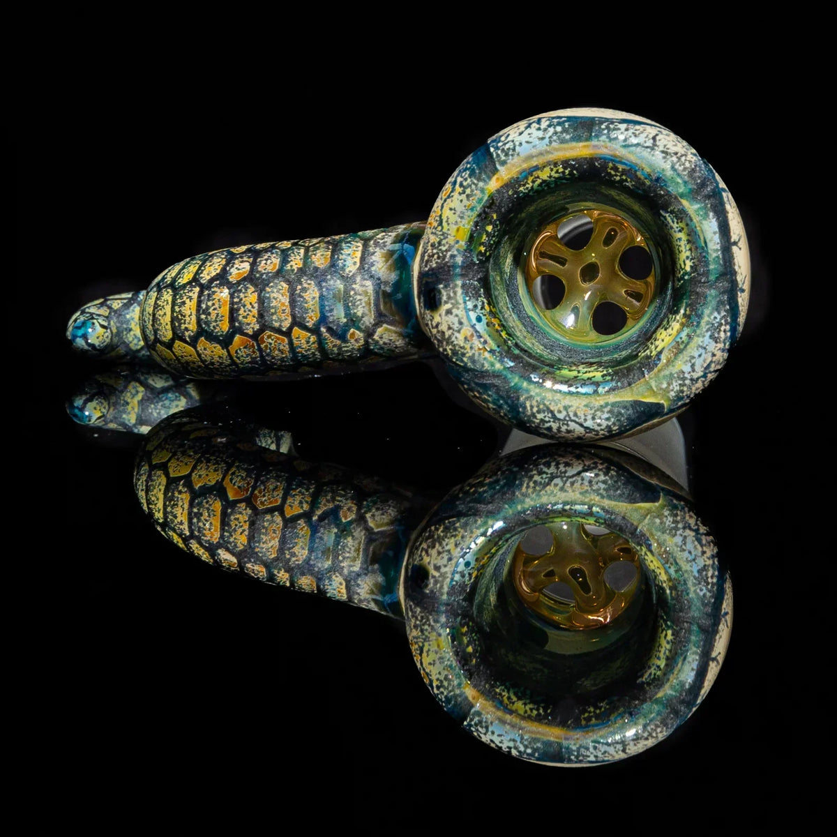 Hand-blown glass pipe with textured reptile scale design on black reflective surface