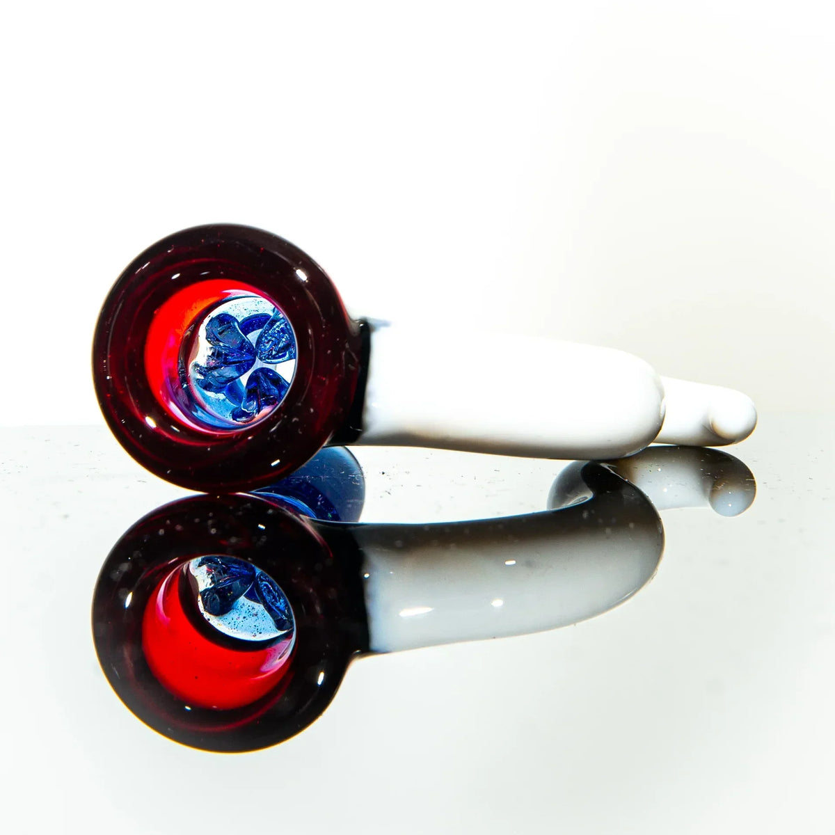 White glass hand pipe with red bowl and blue glass detail, displayed on reflective surface