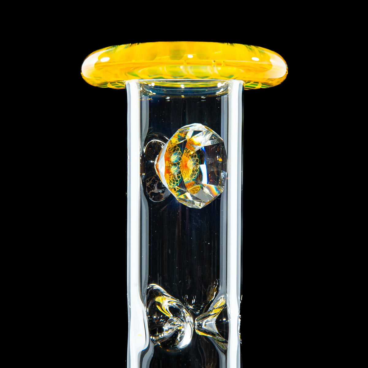 Close-up of a clear glass bong neck with a yellow rim and decorative glass marble detail