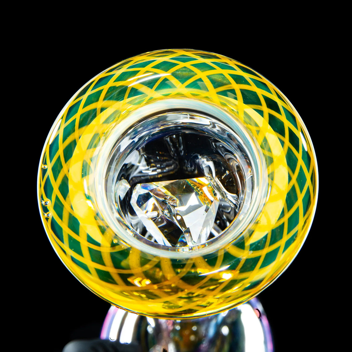 Close-up of a heady glass pipe with yellow and green lattice design and faceted glass details.