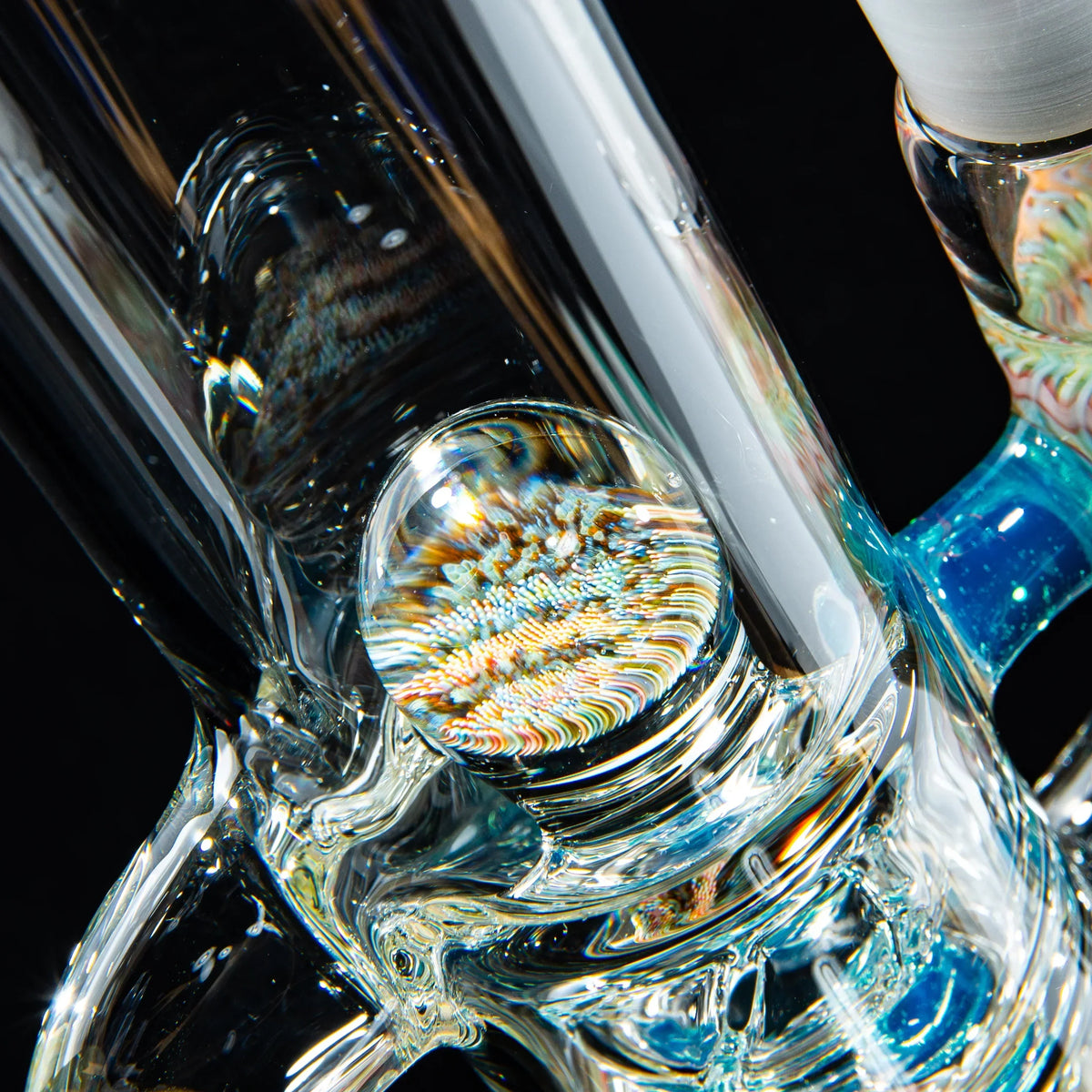 Close-up of intricate, clear heady glass pipe with colorful implosion marble detail