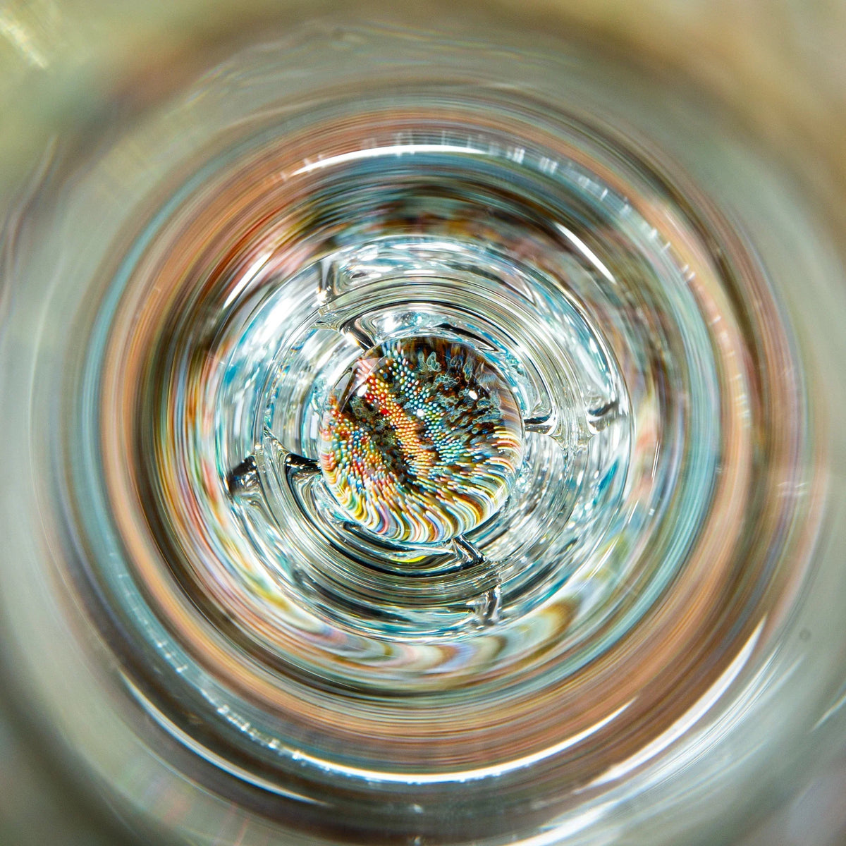 Intricate glass art marble with colorful patterns inside a clear glass pipe, macro view.