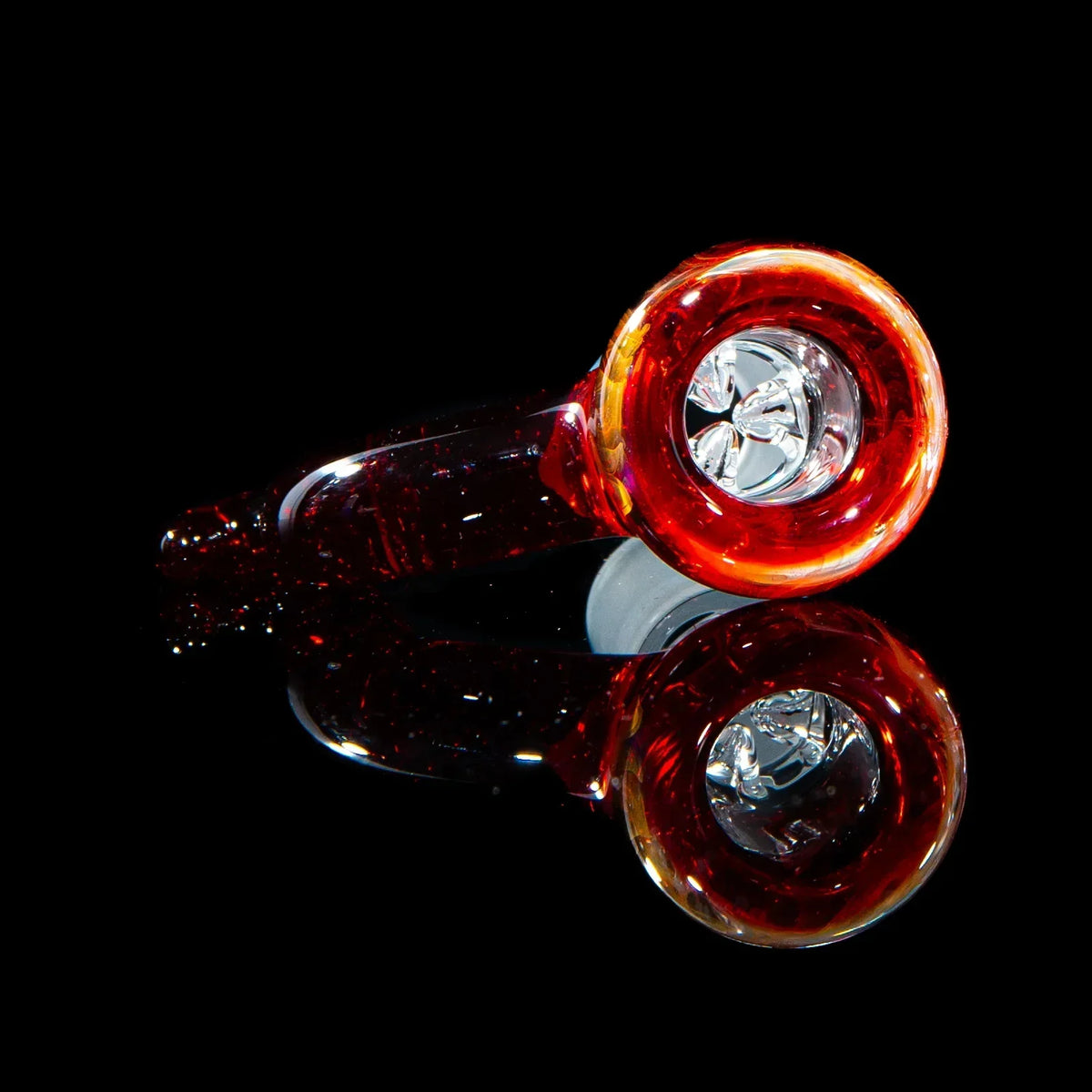 Red glass hand pipe with clear bowl on black reflective surface