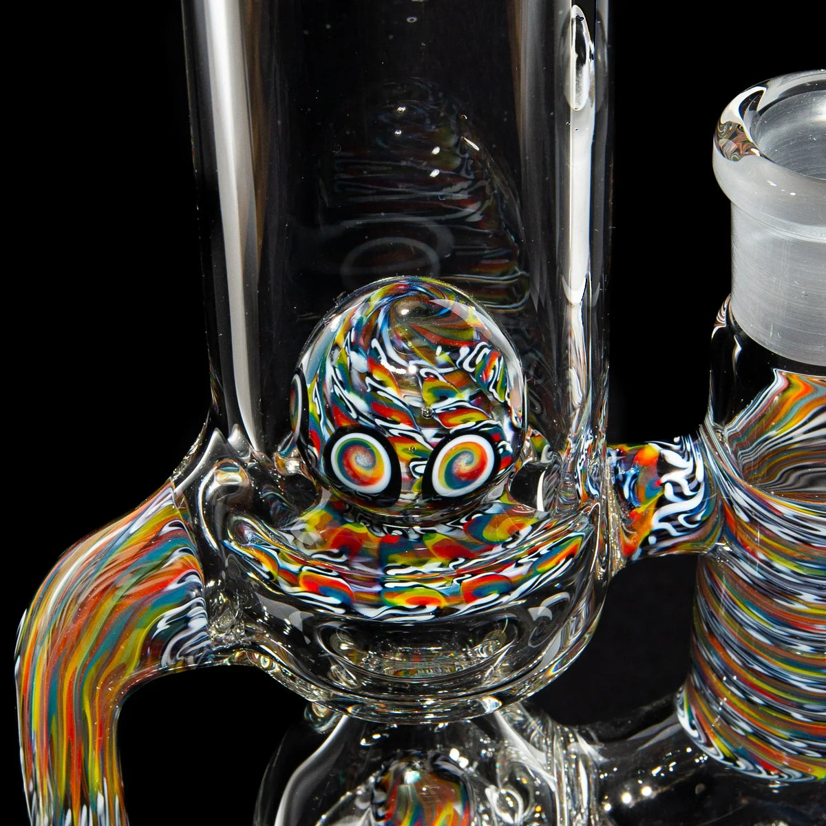 Close-up of a clear glass water pipe with colorful psychedelic swirl accents and marble detail.