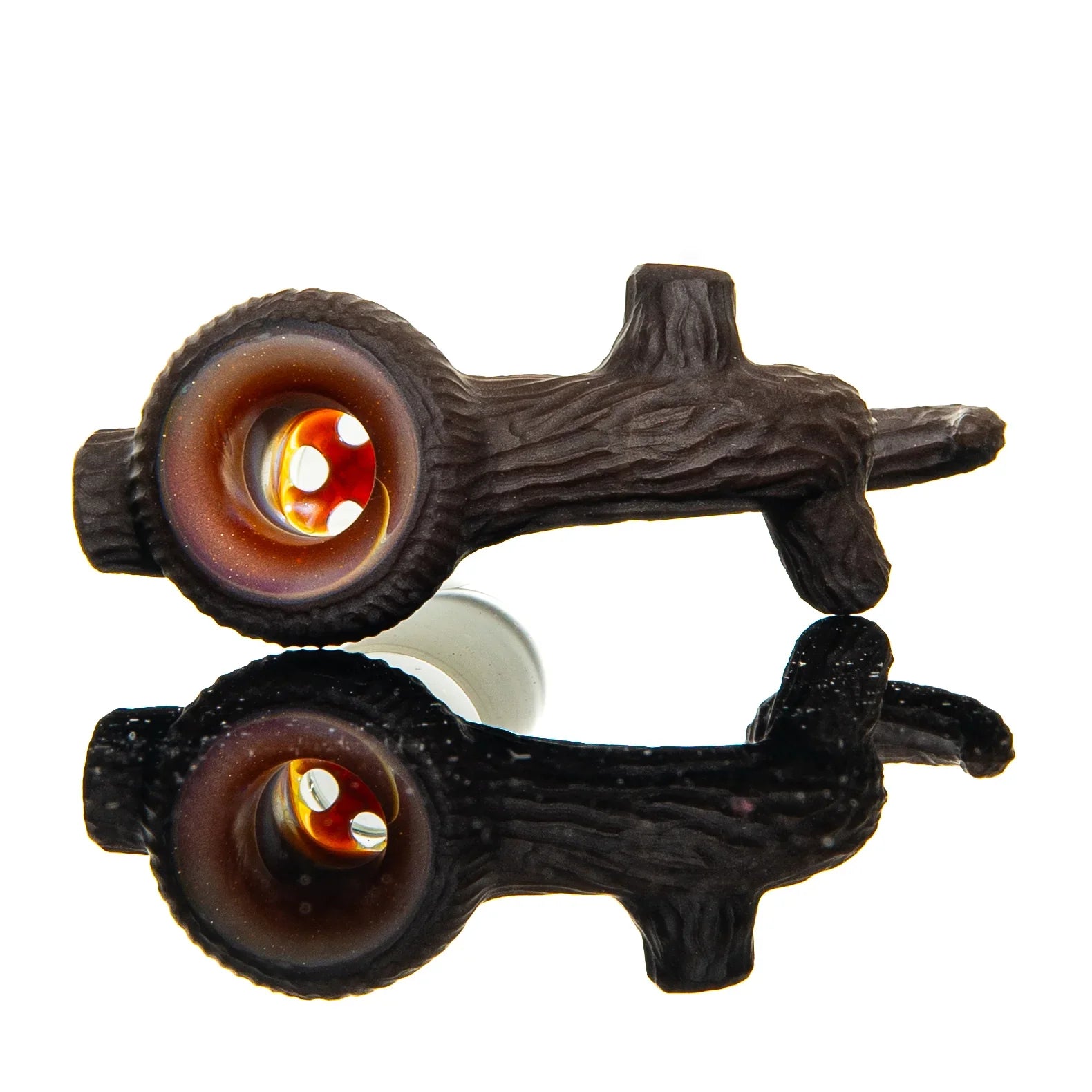 Glass hand pipe shaped like a tree branch with a textured wood design, reflected on surface