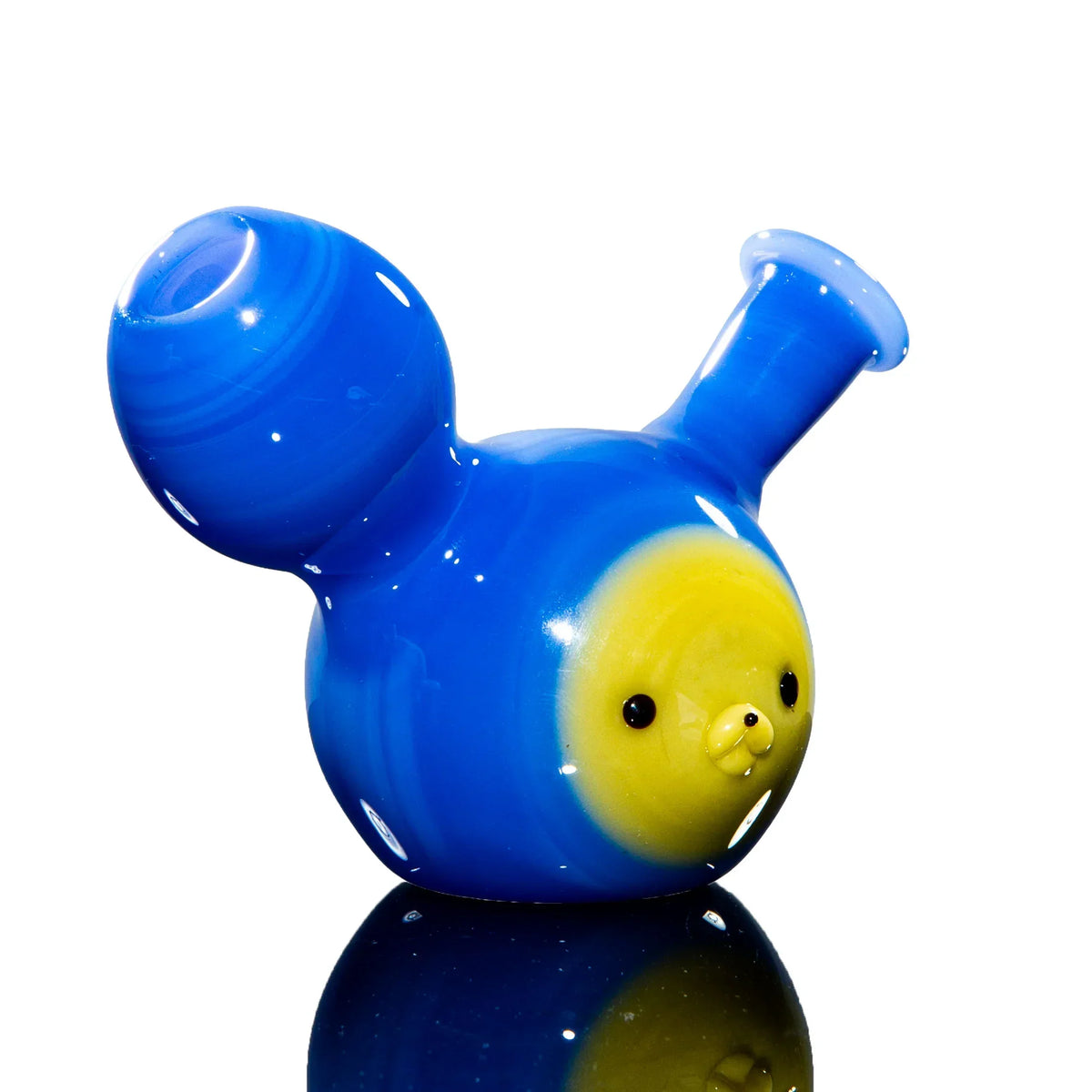 Blue and yellow glass water pipe with a cute animal face design on a reflective surface