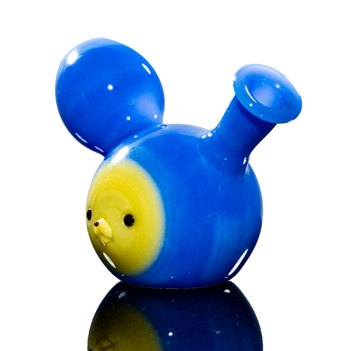 Blue and yellow animal-shaped glass pipe with large ears on reflective surface