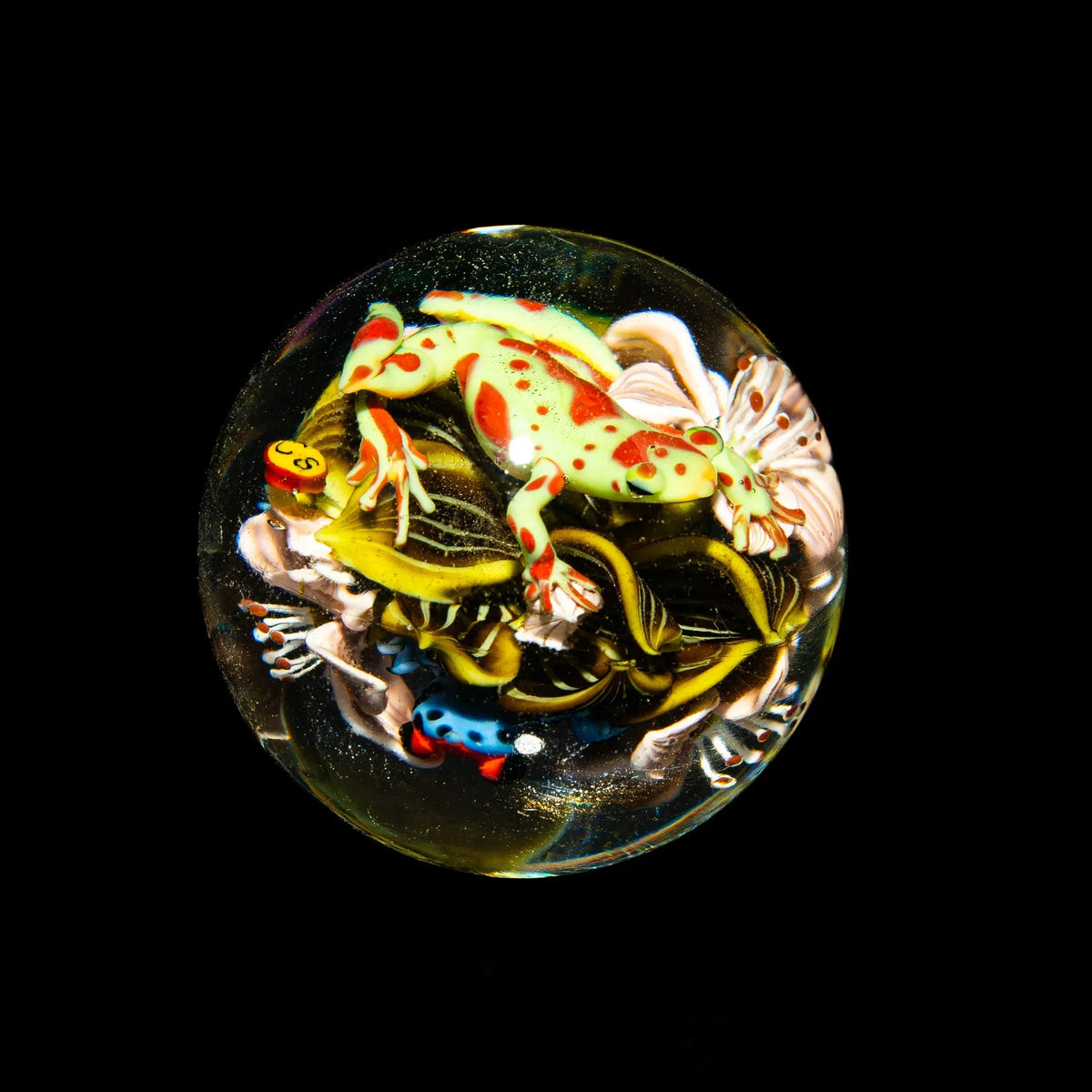 Handcrafted glass marble with colorful frog and intricate floral designs on black background