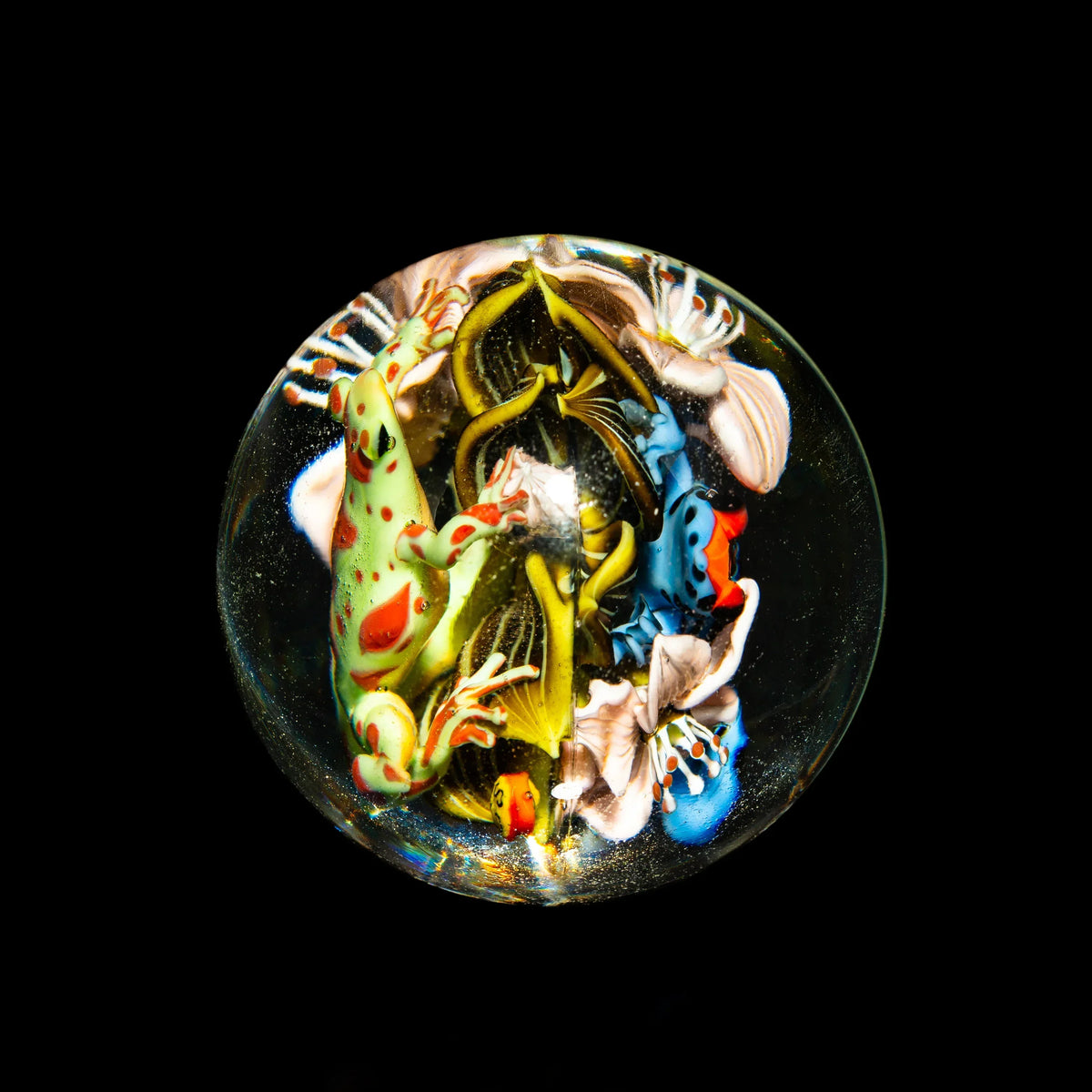 Handcrafted glass marble with detailed frog and floral designs on a black background