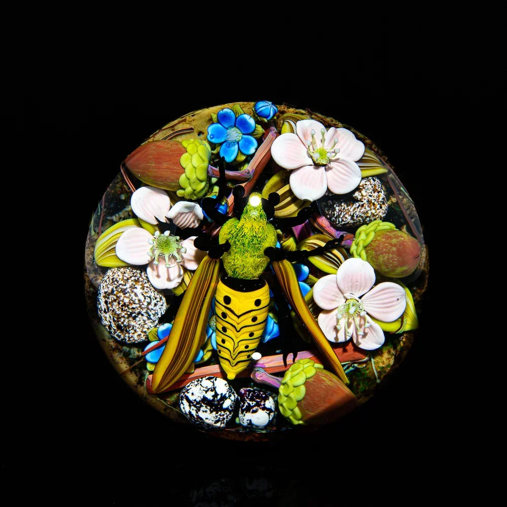Intricate glass art featuring a colorful bee and flowers on a dark background