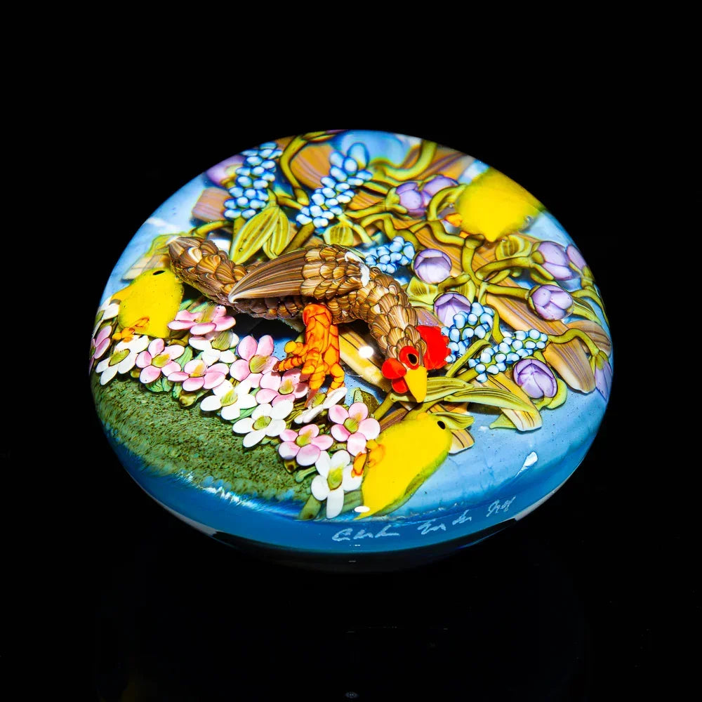 Colorful glass art piece featuring a chicken, chicks, and flowers on a round surface