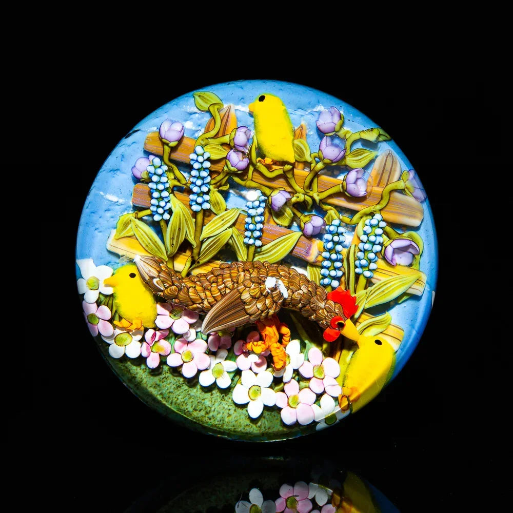 Colorful glass art disc with birds, flowers, and detailed nature scene on a black background