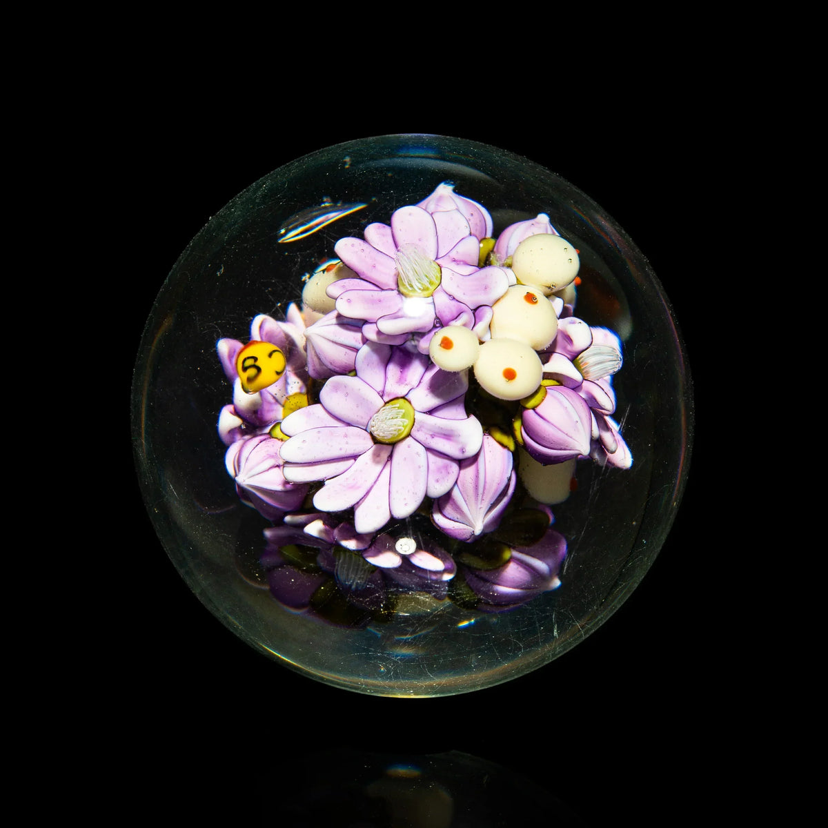 Handcrafted glass marble with detailed pink and white flower bouquet design on black background
