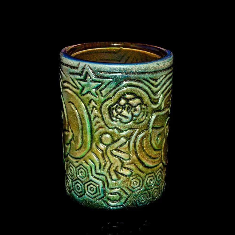 Handcrafted glass tumbler with embossed abstract and geometric patterns on a black background.