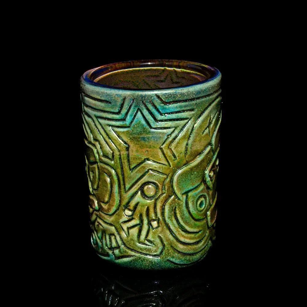 Green ceramic candle holder with abstract engraved star and geometric patterns on black background