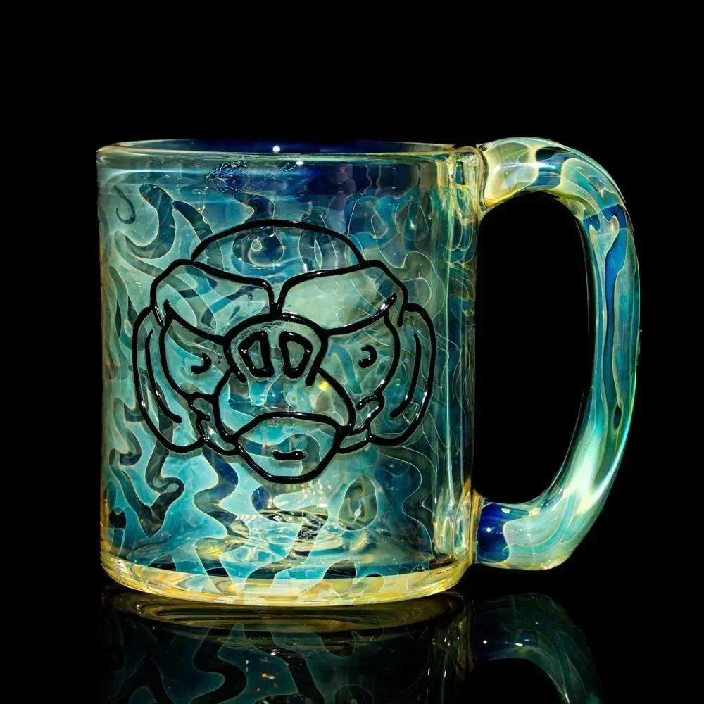 Heady glass mug with abstract face design and blue swirl pattern on a black background