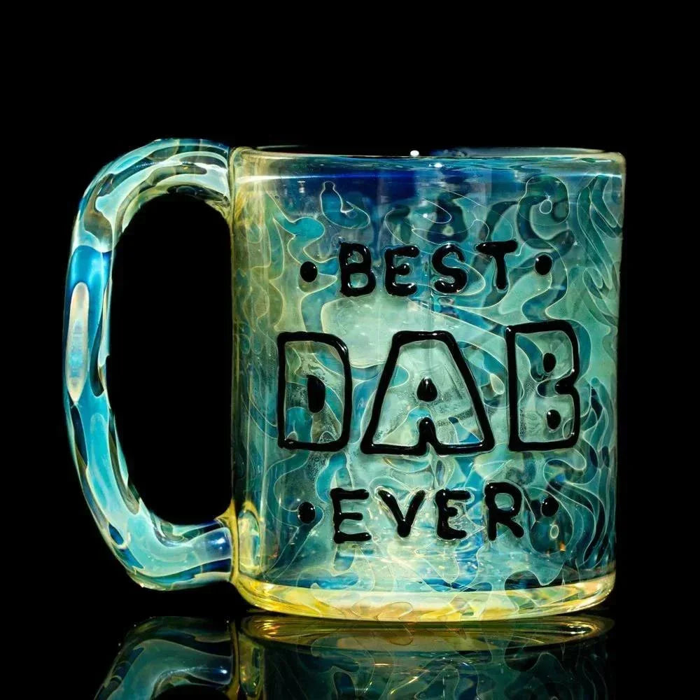 Blue and yellow art glass mug with BEST DAB EVER text, swirled pattern, reflective surface