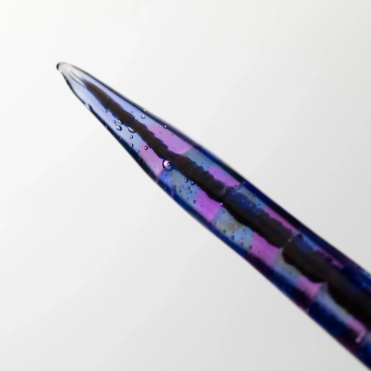 Close-up of colorful glass dabber with purple and blue swirls and small air bubbles.