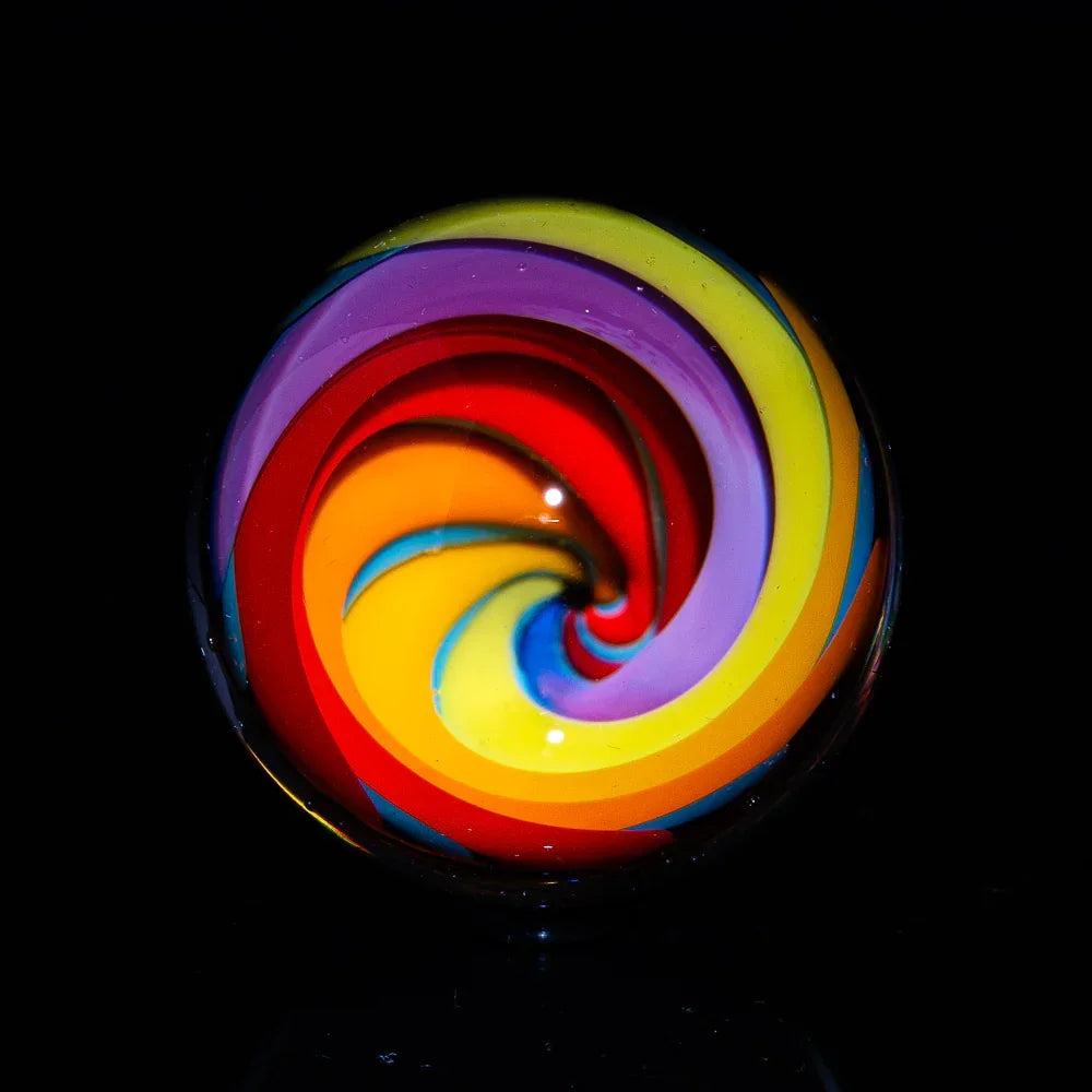 Colorful heady glass marble with swirling rainbow pattern on a black background
