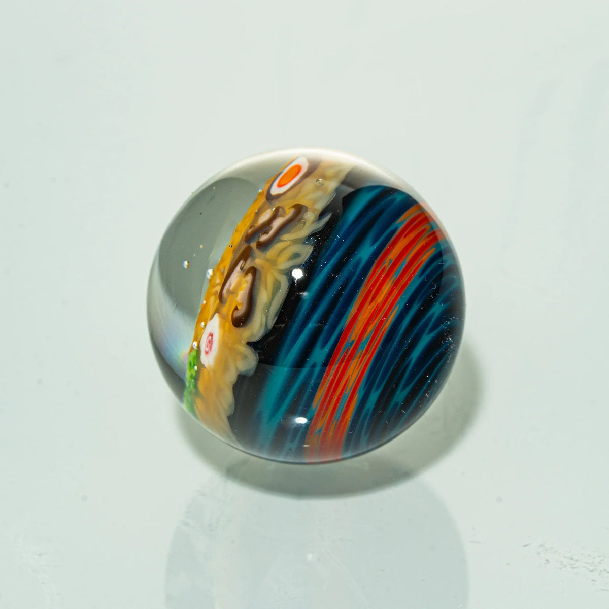 Handcrafted glass marble with vibrant blue, red, and yellow artistic patterns